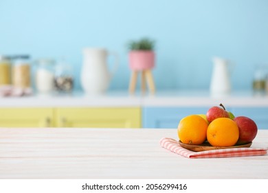 Plate with oranges and apples on table in modern kitchen