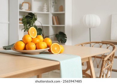 Plate with oranges on dining table in room