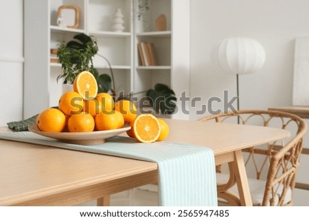 Plate with oranges on dining table in room