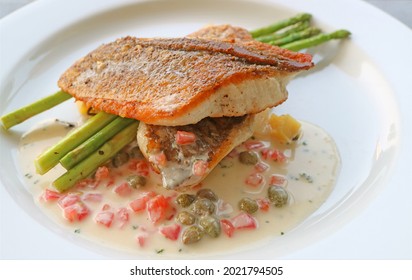 Plate Of Pan Seared Sea Bass With Tomato Caper Mustard Cream Sauce