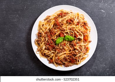 plate of pasta bolognese on dark background.