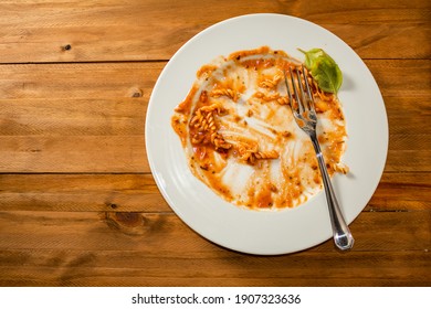 Plate Of Pasta With Sauce Finished And Dirty On A Wooden Table. Top View