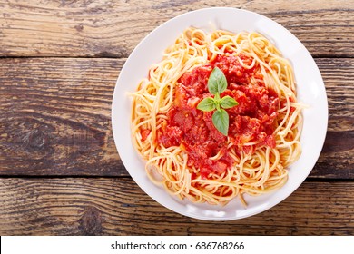 Plate Of Pasta With Tomato Sauce And Green Basil On Wooden Table, Top View