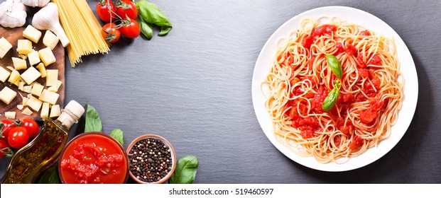 Plate Of Pasta With Tomato Sauce With Ingredients For Cooking On Dark Background, Top View With Copy Space