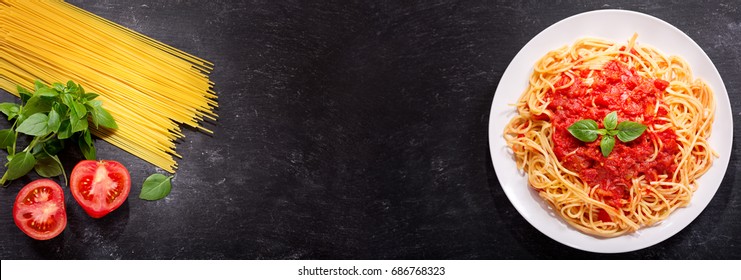 Plate Of Pasta With Tomato Sauce And Ingredients For Cooking On Dark Background, Top View