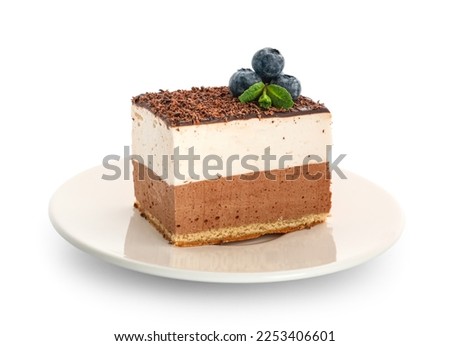 Plate with piece of birds milk cake, blueberries and mint leaves on white background
