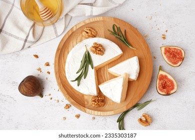Plate with pieces of tasty Camembert cheese on light background