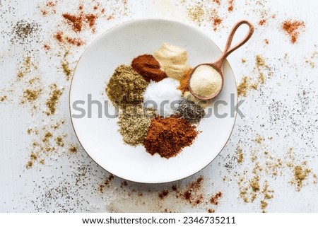 A plate with piles of spices used to make a taco seasoning blend.