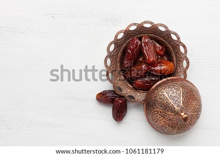 Plate of pitted dates on a white wooden background. Top view