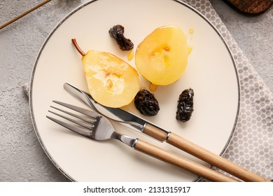 Plate with poached pears, prunes and cutlery on table, closeup
