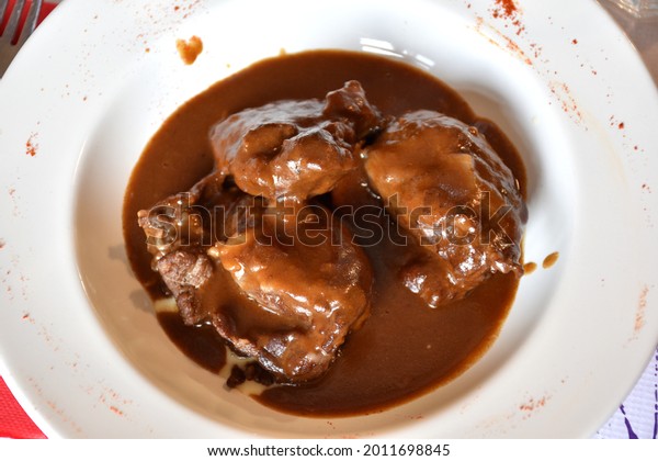 Plate of pork cheeks in red wine. Wine sauce and\
applesauce as a base.