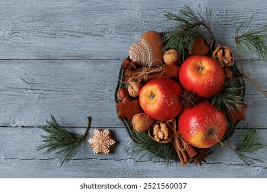 Plate with red apples, cinnamon, cookies, gingerbread, nuts and pine branches on wooden background. Christmas card, copy space. - Powered by Shutterstock