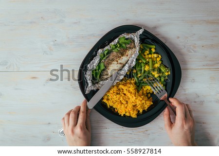plate with rise fish and vegetables with woman hands