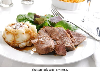 A Plate Of Roast Beef And Mashed Potatoes With A Side Of Macaroni And Cheese