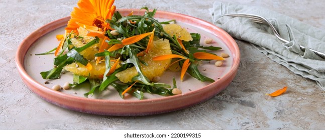 Plate With Salad With Arugula, Oranges And Edible Calendula Flowers On A Light Table