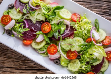 Plate of salad with vegetables on rustic oak table.