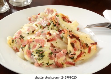 A Plate Of Scalloped Potatoes With Creamy Cheese Sauce And Ham