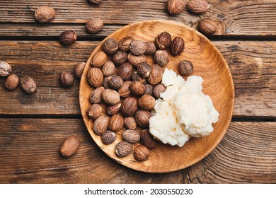 Plate with shea butter and nuts on wooden background