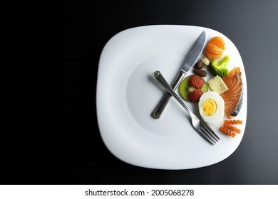 a plate simulating a clock with the hands of a fork and a knife showing food, concept of intermittent fasting - Shutterstock ID 2005068278