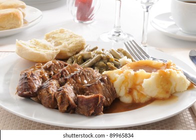 A Plate Of Sliced Beef Pot Roast With Mashed Potatoes And Mushroom Gravy