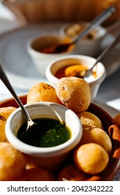 a plate with some papas arrugadas, wrinkly potatoes in Spanish, typical of the Canarian Islands, and some bowls with different mojo sauces, such as green mojo, red mojo or mojo picon, on a table - Shutterstock ID 2042342222
