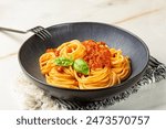 A plate with Spaghetti with vegan bolognese sauce made from soya, tomato and vegetables. Vegetarian pasta. Light table surface. Copy space.