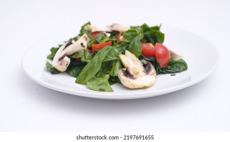 A Plate With Spinach Salad, Tomatoes And Mushrooms