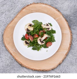 A Plate With Spinach Salad, Tomatoes And Mushrooms