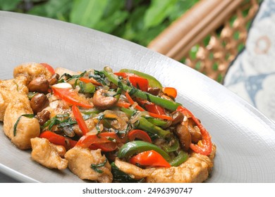 A plate of stir-fried chicken with an assortment of colorful vegetables, including bell peppers, mushrooms, and bright green herbs, garnished with roasted nuts. - Powered by Shutterstock