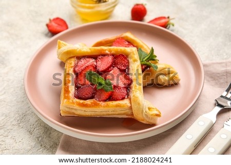 Plate with strawberry puff pastry and mint leaves on table, closeup