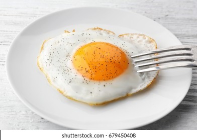 Plate With Sunny Side Up Fried Egg On Wooden Table