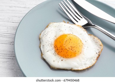 Plate With Sunny Side Up Fried Egg On Wooden Table