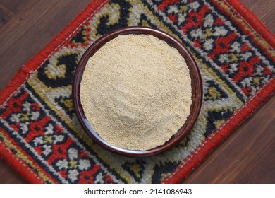 A plate with talkan (coarse flour from fried barley or wheat) on a wooden background. - Shutterstock ID 2141086943
