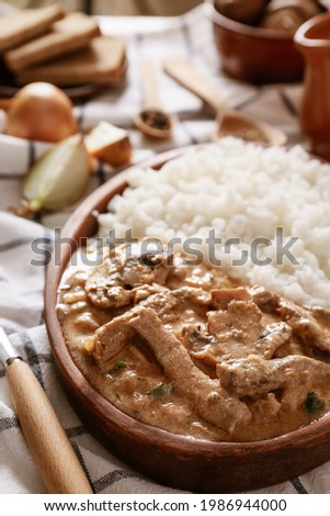 Plate with tasty beef stroganoff and rice on table, closeup