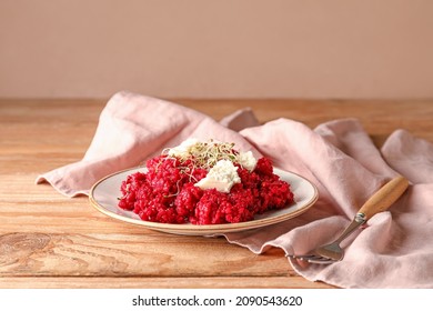 Plate with tasty beet risotto on wooden background