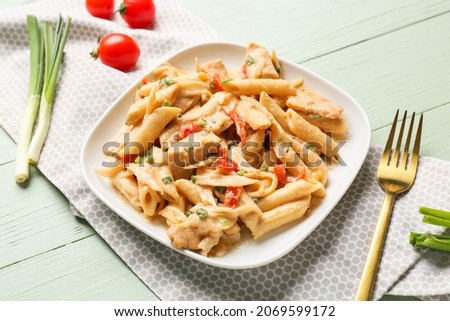 Plate with tasty cajun chicken pasta on color wooden background, closeup