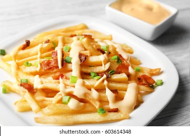 Plate With Tasty Cheese Fries And Sauce On White Wooden Table