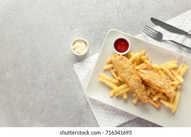 Plate With Tasty Fried Fish And Chips On Table