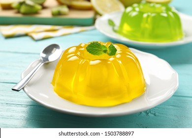 Plate of tasty fruit jelly and mint on blue wooden table, closeup