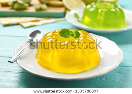 Plate of tasty fruit jelly and mint on blue wooden table, closeup