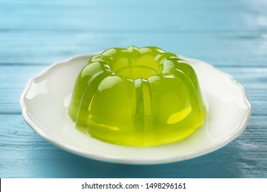 Plate of tasty fruit jelly on blue wooden table, closeup