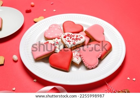 Plate of tasty heart shaped cookies on red background, closeup. Valentine's Day celebration