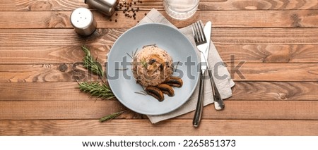 Plate with tasty mushroom risotto on wooden table, top view