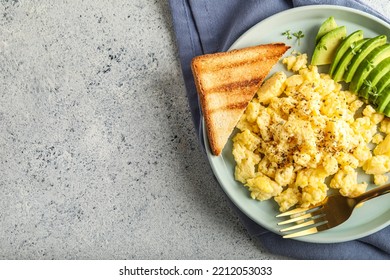 Plate With Tasty Scrambled Eggs, Avocado And Toast On Light Background