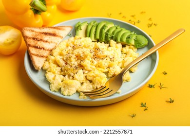 Plate With Tasty Scrambled Eggs, Toast And Avocado On Yellow Background