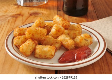 A Plate Of Tater Tots And Catsup, Served As An Appetizer With Beer On A Bar Counter