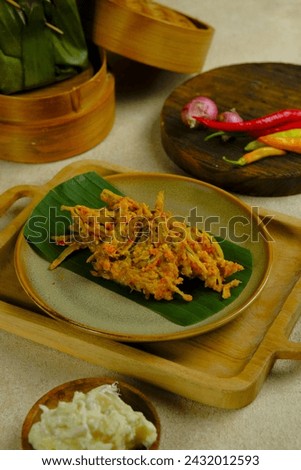 A plate of Tempoyak Ikan Teri or Otun on brown background. Anchovy fish with tempoyak, chili, onion and turmeric. Tempoyak made from fermented durian fruit. Makanan tradisional