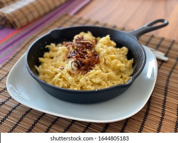 A plate of traditional Austrian Cheese Spaetzle ("Käsespätzle") served in a cast-iron pan - Shutterstock ID 1644805183