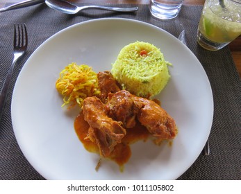 A Plate Of The Traditional Meal Chicken Curry With Yellow Rice And Side Of Cabbage In A Restaurant In Mauritius