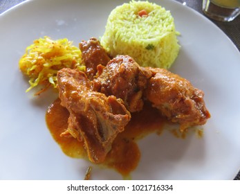 A Plate Of The Traditional Meal Chicken Curry With Yellow Rice And Side Of Cabbage In A Restaurant In Mauritius